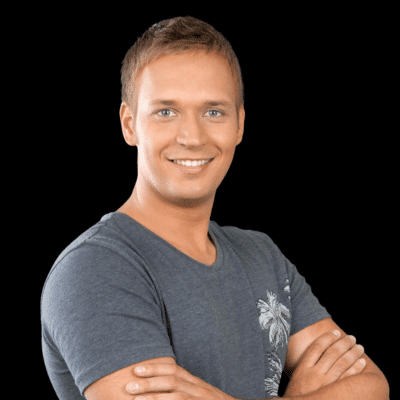 Smiling man with arms crossed wearing gray t-shirt on black background.