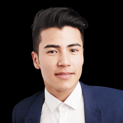 Portrait of a young man with dark hair wearing a blue blazer and white shirt, smiling at the camera.