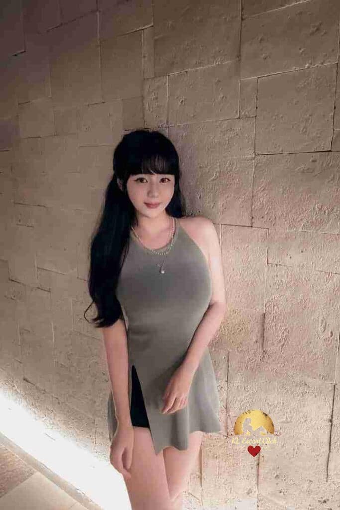 Attractive Asian woman with long black hair posing against a textured wall.