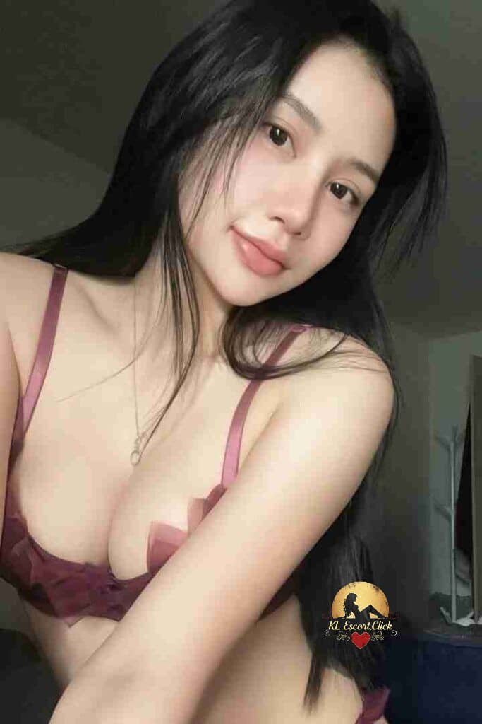 Beautiful Asian woman with long black hair and a maroon bra top smiling softly at the camera.