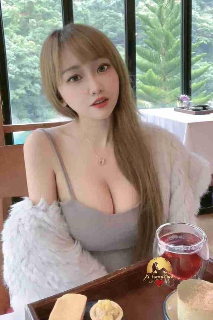 Attractive Asian woman with blonde hair, grey top, and fur shawl at a table.