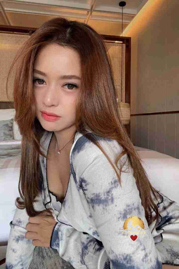 KL Escort Girl Woman in blue lace lingerie smiles while lying on a bed. Sex Call Girl