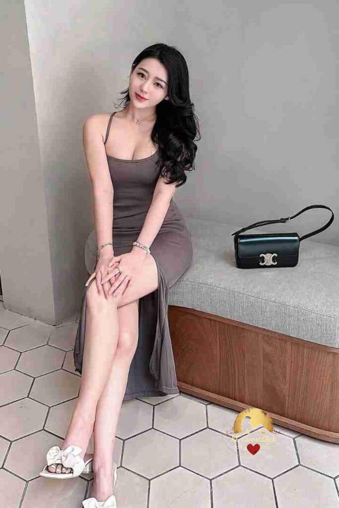 Attractive Asian woman in dress sitting, KL escort style.