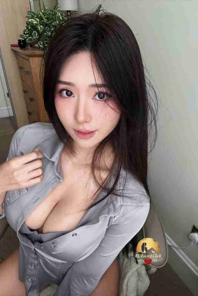 Attractive Asian woman in gray shirt with open collar, long dark hair, and soft makeup.