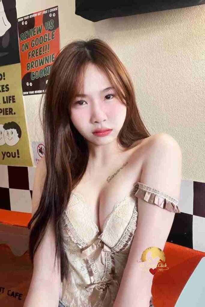 Attractive Asian woman in lace top with shoulder tattoo, cafe background.