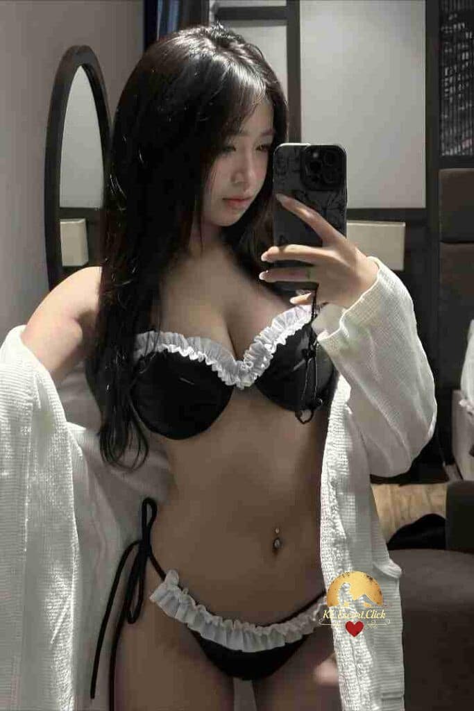 Attractive Asian woman in lingerie and robe taking selfie.