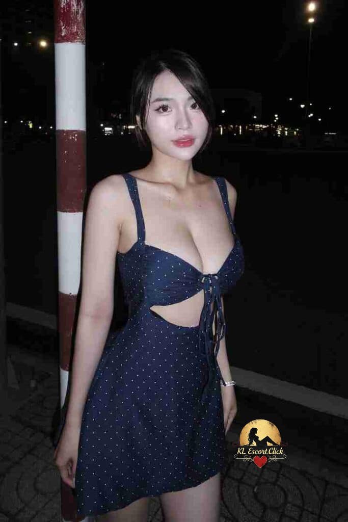 Attractive Asian woman in polka dot dress posing outdoors at night.