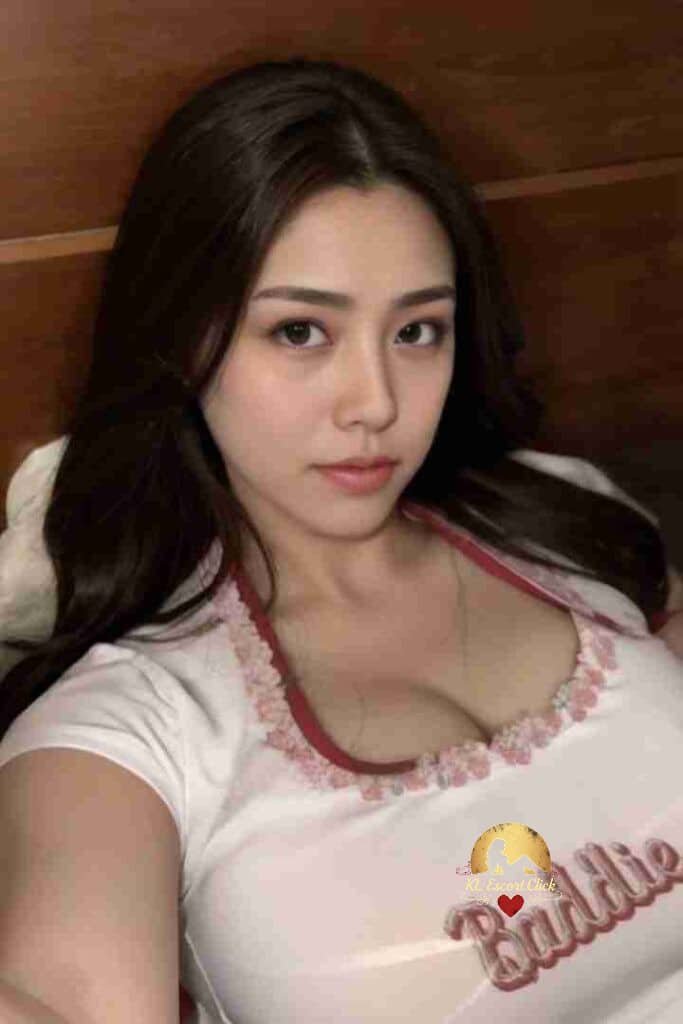 Attractive Asian woman with long dark hair wearing a white top that says "Baddie".
