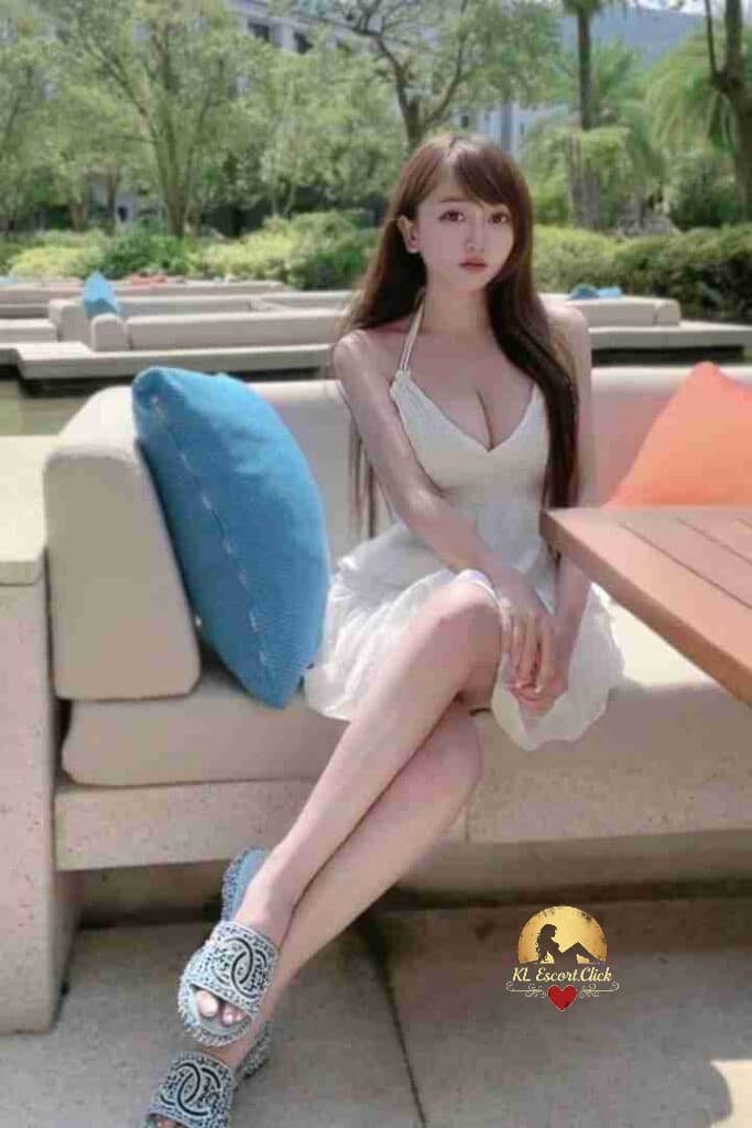 Beautiful Asian woman in white dress on outdoor couch. KL Escort.
