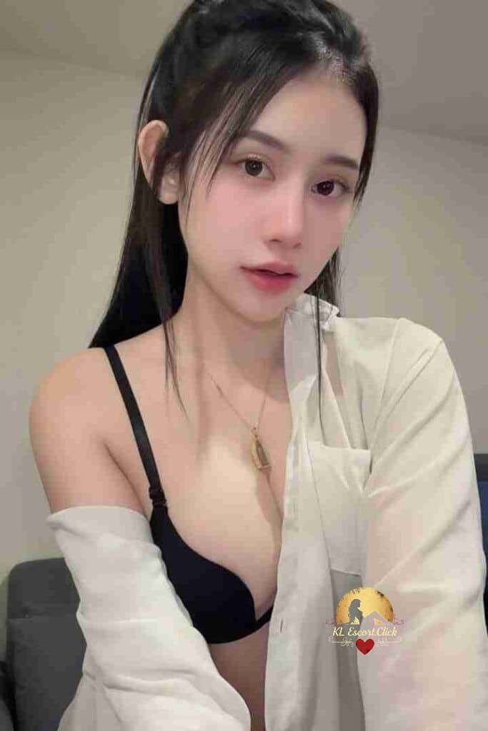 Attractive Asian woman in white shirt and black bra with necklace looking at the camera.