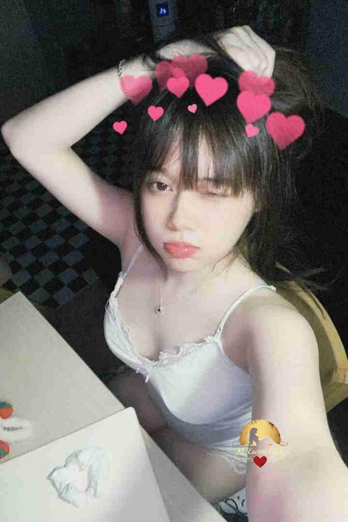 Attractive Vietnamese woman with bangs and hearts filter, posing indoors. KL escort.