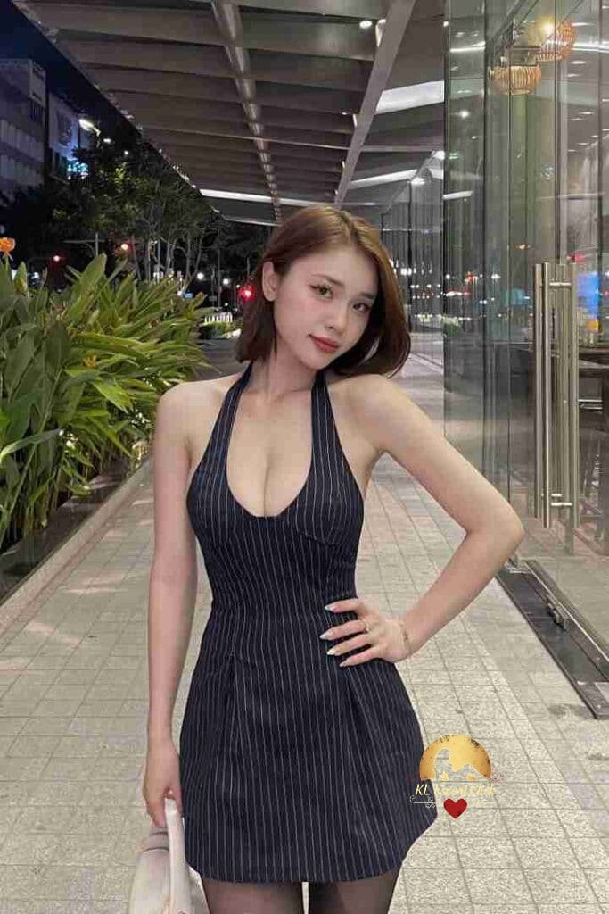Attractive Vietnamese woman in halter dress posing outdoors at night.