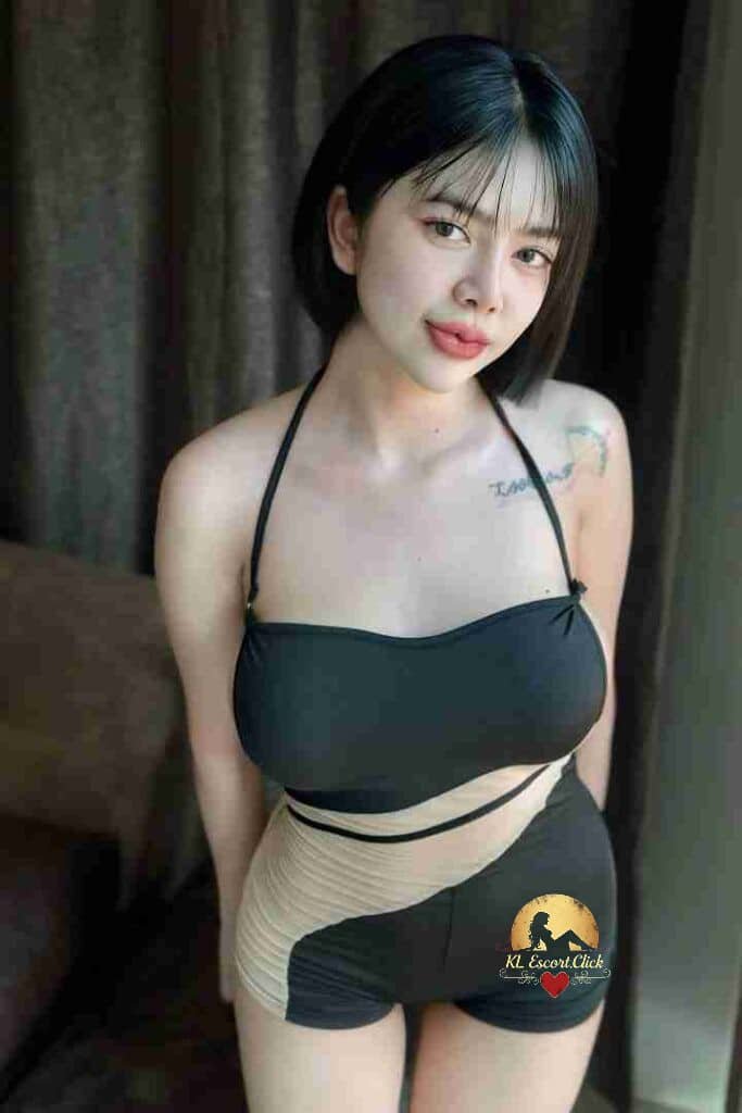 Woman in black and beige swimsuit with bob haircut and shoulder tattoo posing indoors.