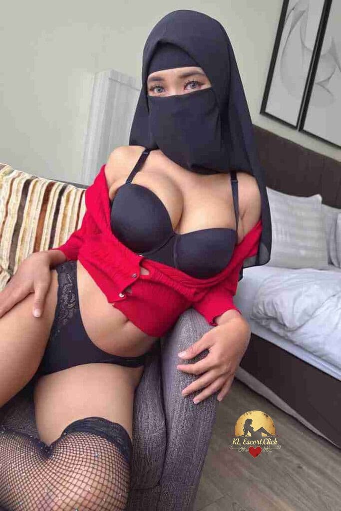 Woman in hijab, lingerie, and red cardigan sitting on a chair.