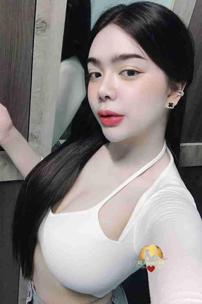 Glamorous woman with long dark hair, wearing a white top and earrings, posing indoors.