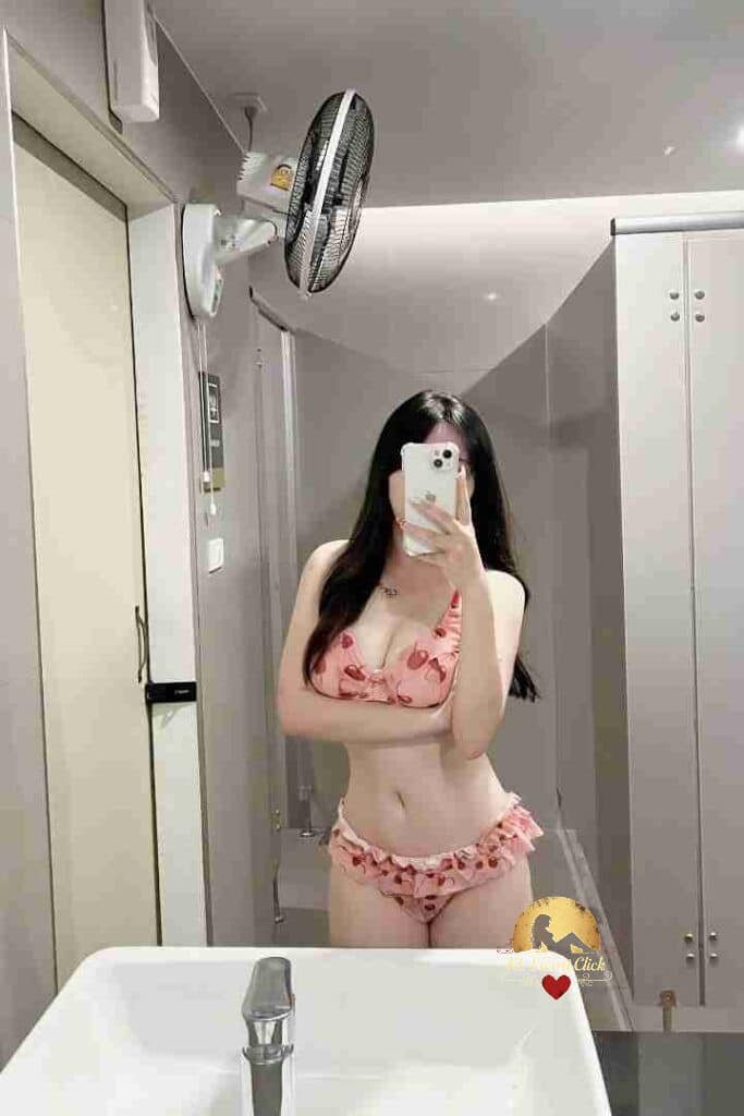 Woman in pink floral bikini taking mirror selfie in bathroom.