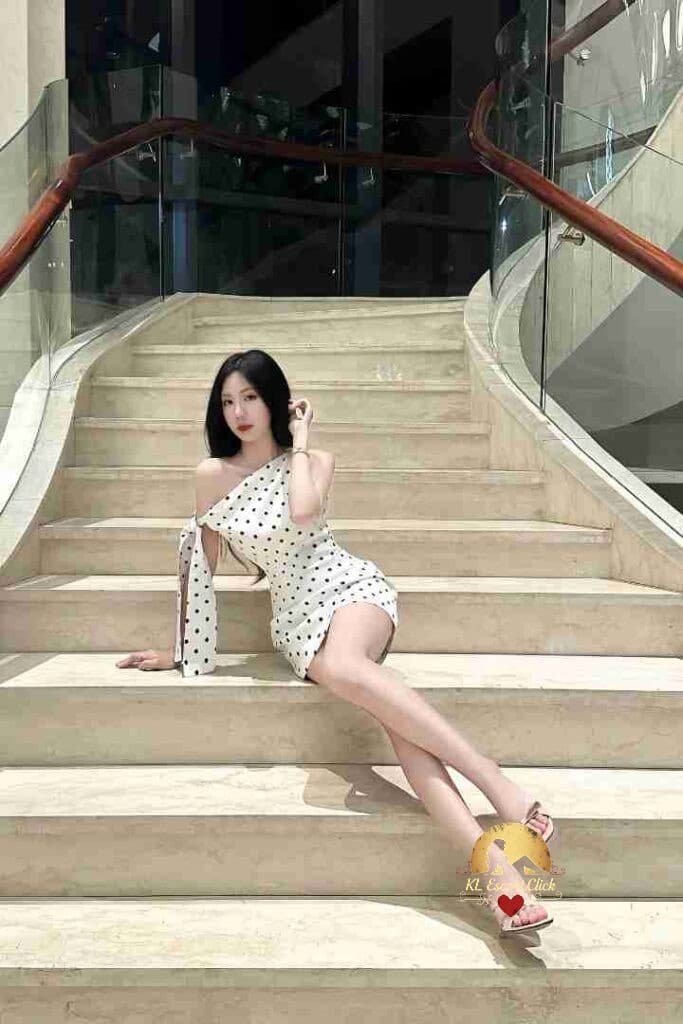 Woman in polka dot dress sits on marble stairs.